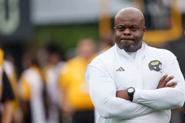 Charles Huff standing on the sideline with arms crossed during a football practice session