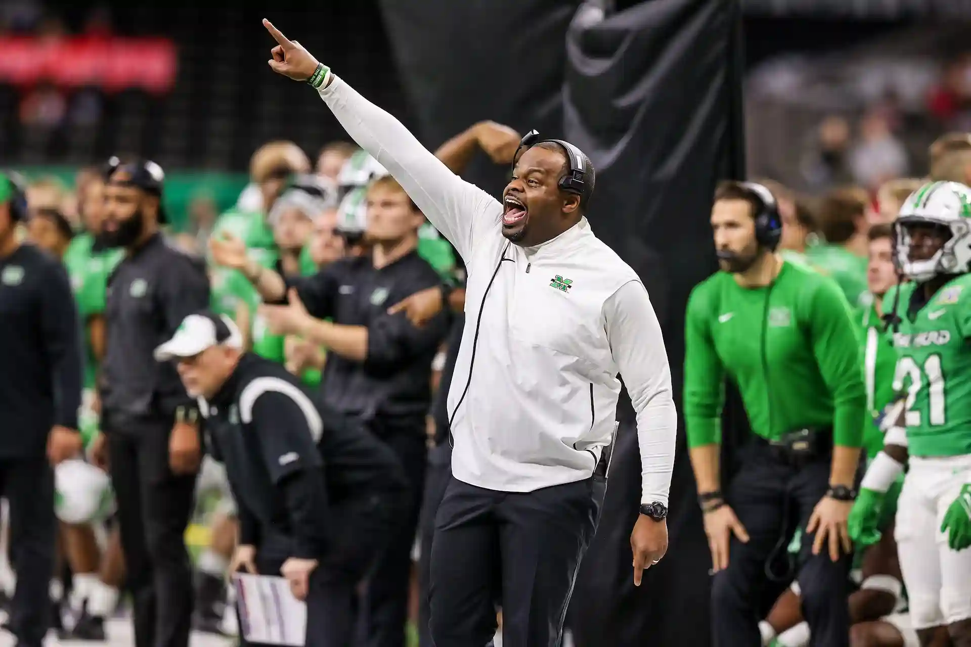 Charles Huff coaching from the sideline while signaling a play during a college football game