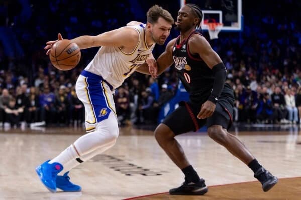 Luka Dončić driving to the basket while being defended by a Philadelphia 76ers player during an NBA matchup.