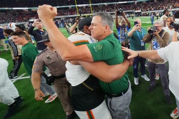 Miami Hurricanes head coach Mario Cristobal celebrates on the field with a player after Miami’s upset win over Ohio State in the Cotton Bowl College Football Playoff quarterfinal.