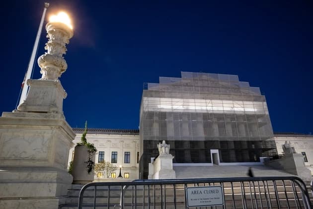 Supreme Court building covered in scaffolding at night with restricted access barriers in front
