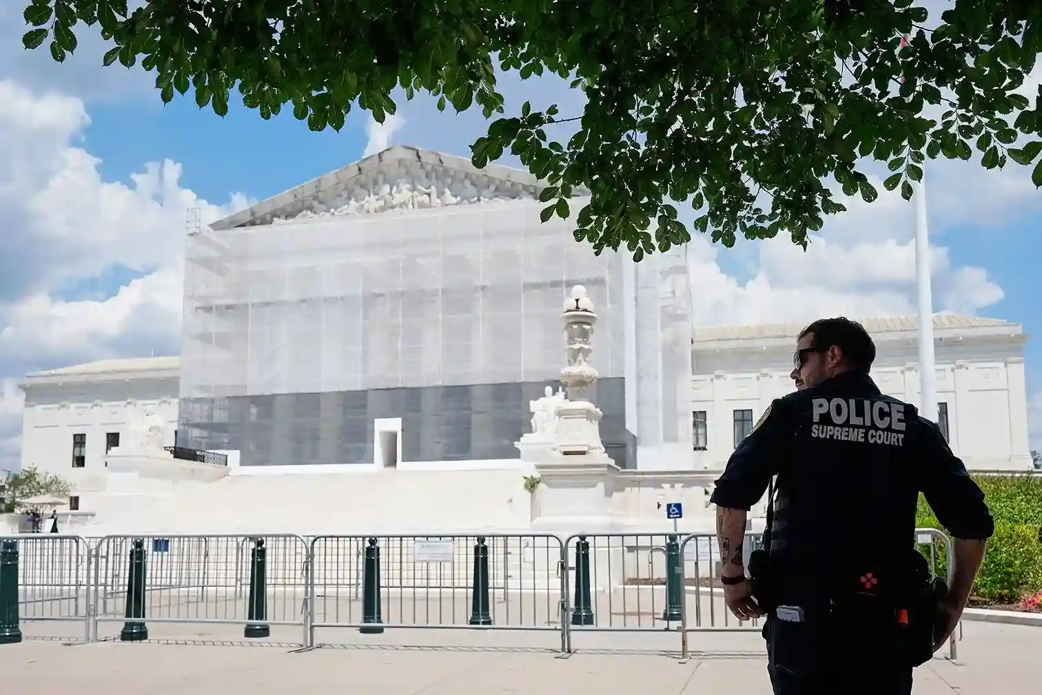 Supreme Court building covered in scaffolding as a Supreme Court police officer stands guard behind security barriers